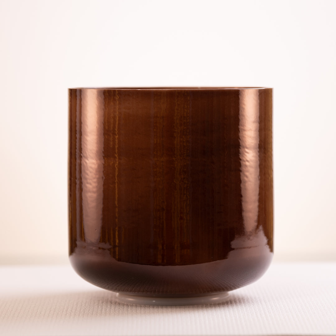 A dark brown, pearlescent singing bowl with a smooth surface, displayed against a neutral background.