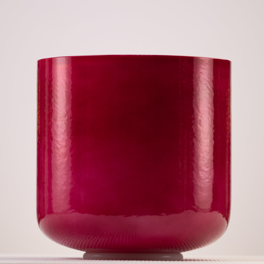 A pearlescent magenta-red crystal singing bowl on a white background.