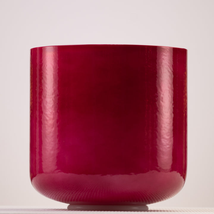 A pearlescent magenta-red crystal singing bowl on a white background.