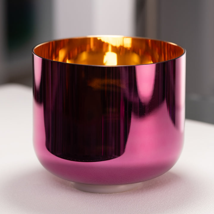 Magenta and gold metallic bowl on a light surface with a blurred background