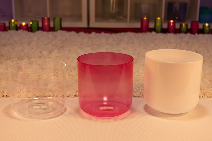 Three Sacred Singing Bowls, displayed on a surface with a blurred background featuring colored lights.