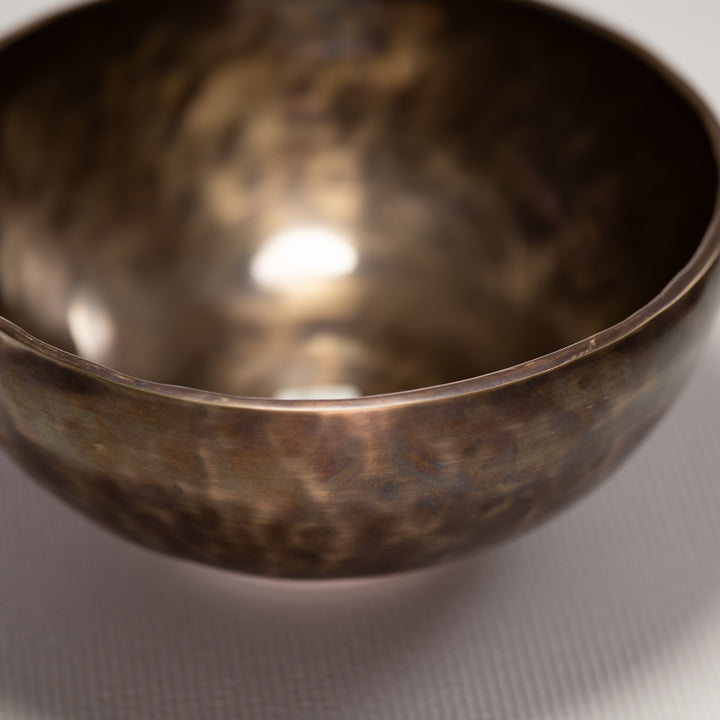 Close-up of a bronze singing bowl on a light gray background