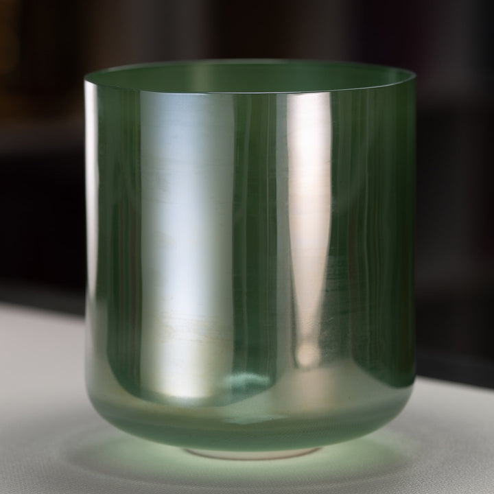 A green quartz crystal singing bowl with a reflective surface on a dark background.