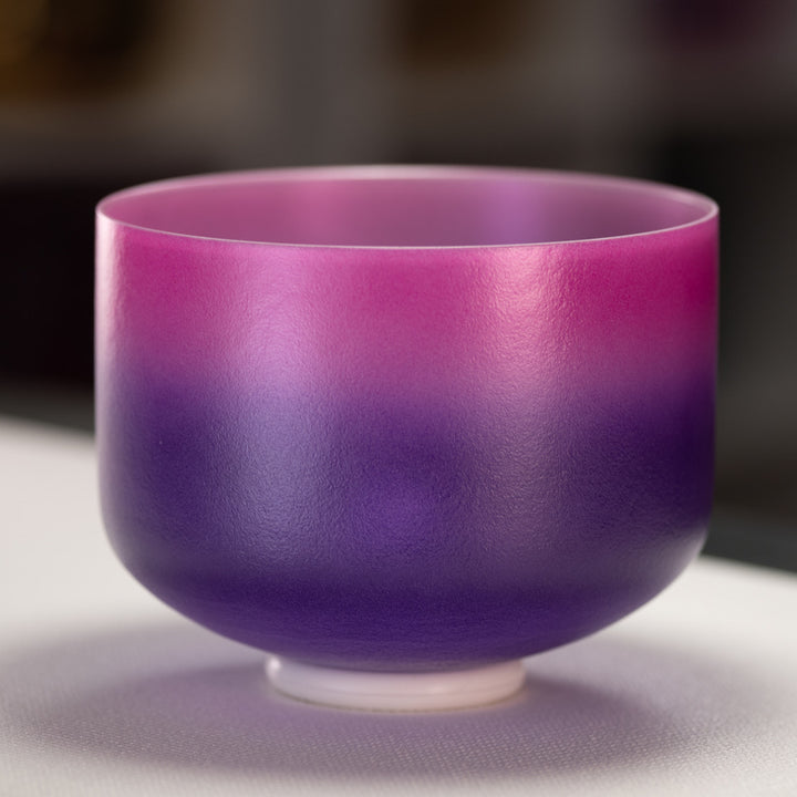 A 10" frosted crystal singing bowl with a gradient of pink to purple color, with a silver interior.