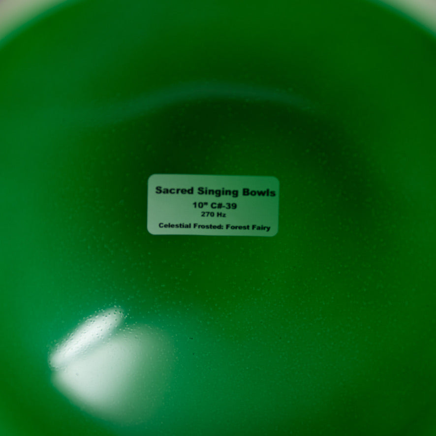 Green singing bowl with a label indicating 'Sacred Singing Bowls' and product details.
