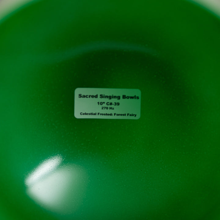 Green singing bowl with a label indicating 'Sacred Singing Bowls' and product details.