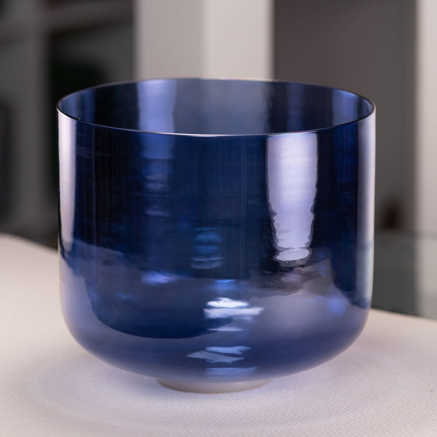 Blue crystal singing bowl on a light surface with a blurred background