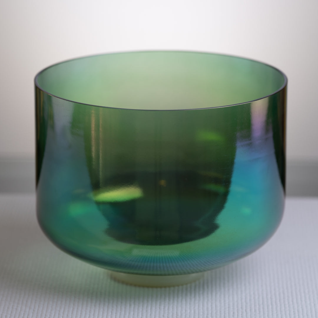 An 11-inch F#-21 Earth Magic Crystal Singing Bowl with a prismatic dark green color, placed on a white surface.