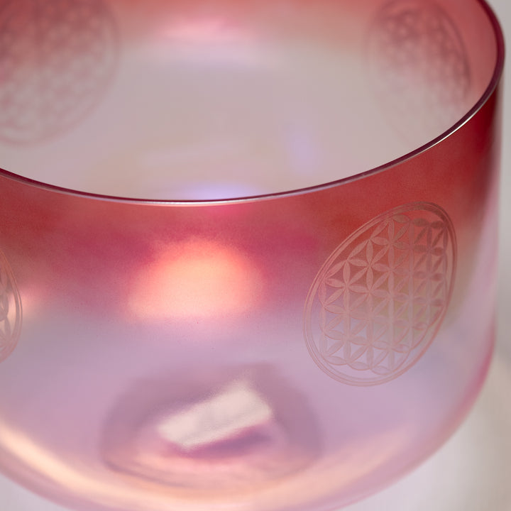 Close-up of a pink crystal singing bowl with a geometric design on a white background