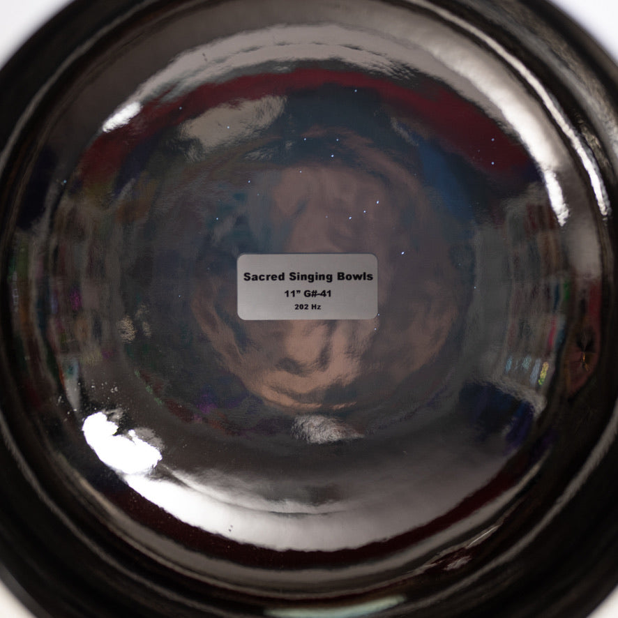 Close-up of a reflective surface with 'Sacred Singing Bowls' label