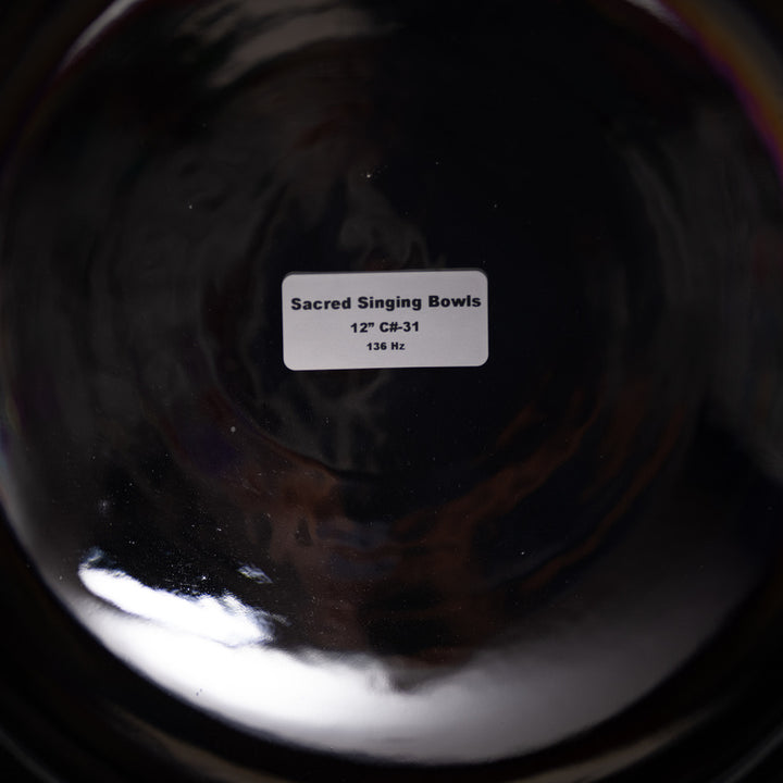 Close-up of a metallic singing bowl with a label indicating 'Sacred Singing Bowls' and specifications.