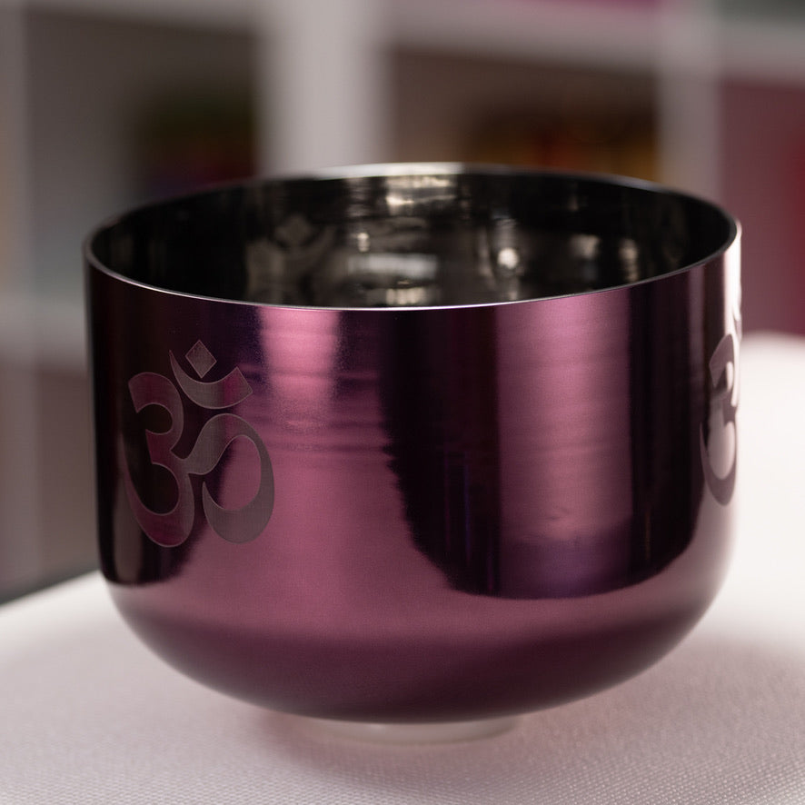 Purple singing bowl with Om symbol on a blurred background