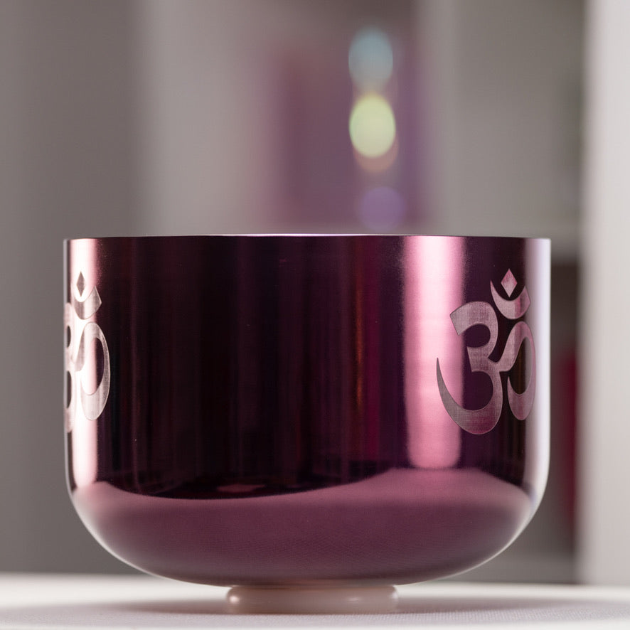 Purple singing bowl with Om symbol on a blurred background