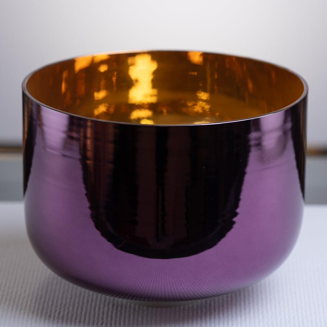A 12-inch purple and gold crystal singing bowl with a reflective surface, placed on a white surface.