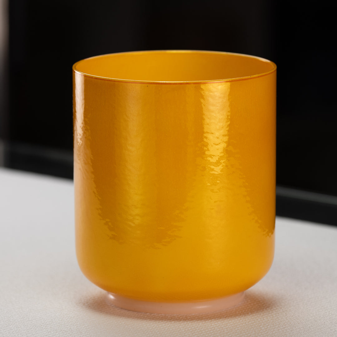 A yellow, 6.25 inch F-8 Honeycomb Singing Bowl made of quartz crystal, with a smooth, round base and a perfect pitch.