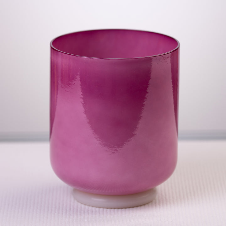A 6.5 inch magenta manifestation crystal singing bowl on a white base, viewed from the front.