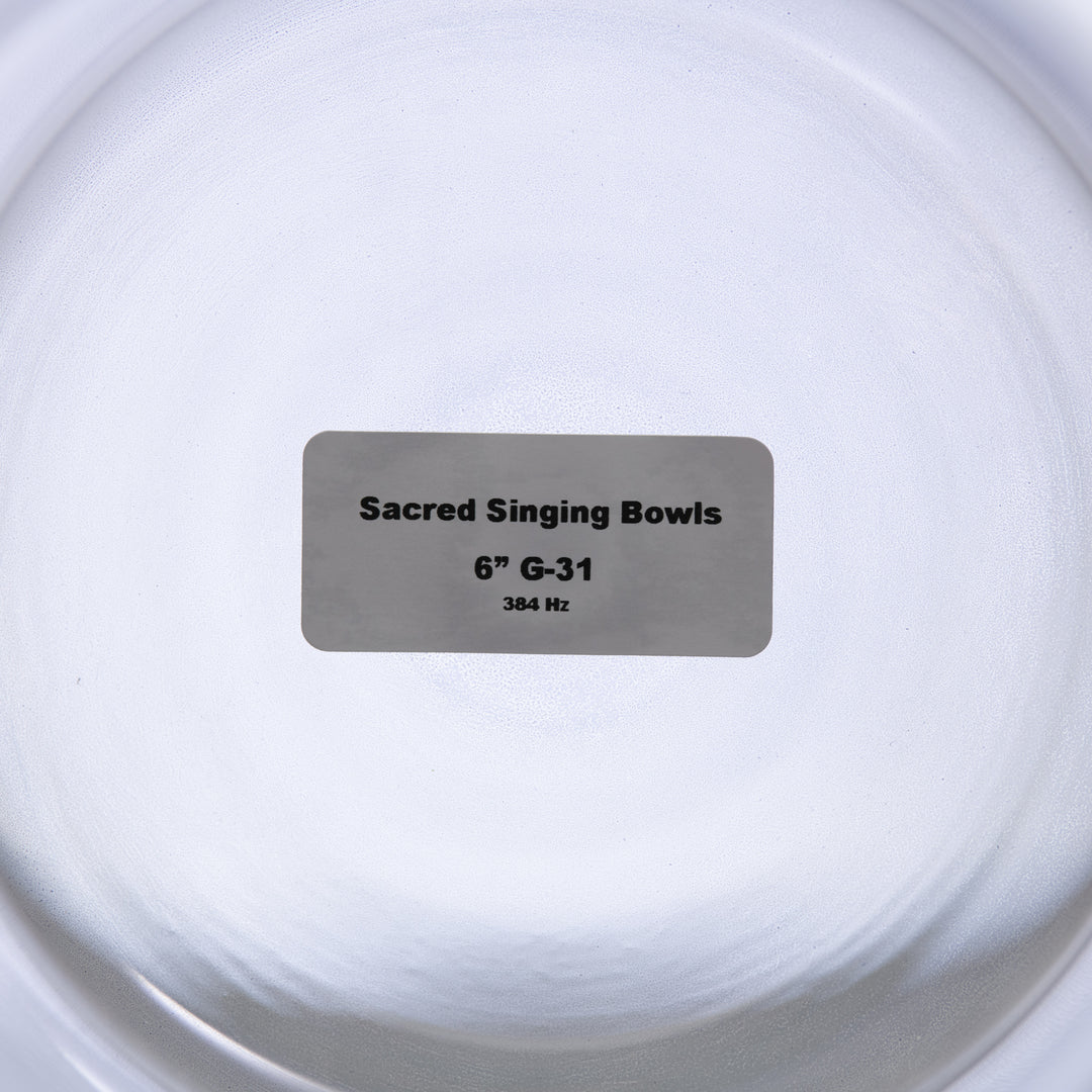 A label placed inside a clear glass singing bowl with the text 'Sacred Singing Bowls 6" G-31 384 Hz'.