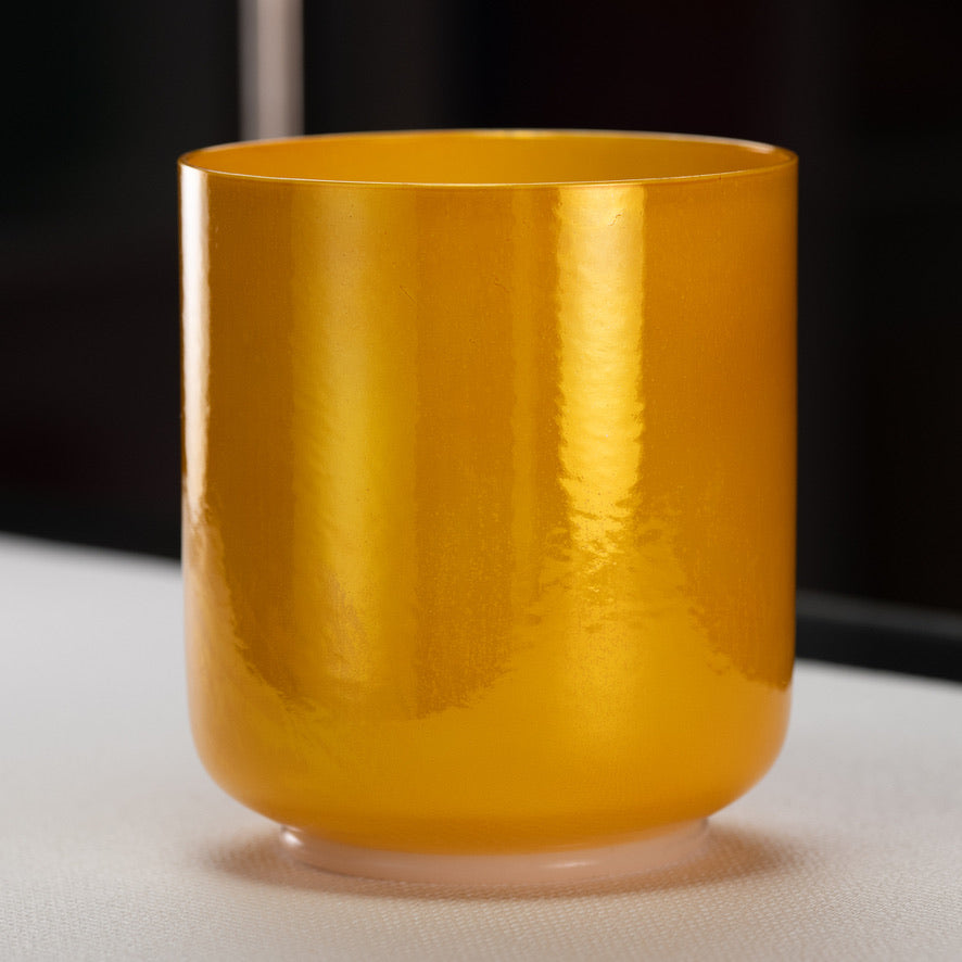 A yellow honeycomb crystal singing bowl on a white surface.
