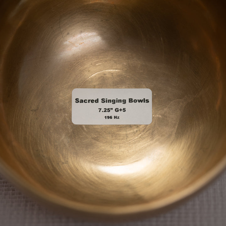 Close-up of a metallic singing bowl with a label indicating specifications.