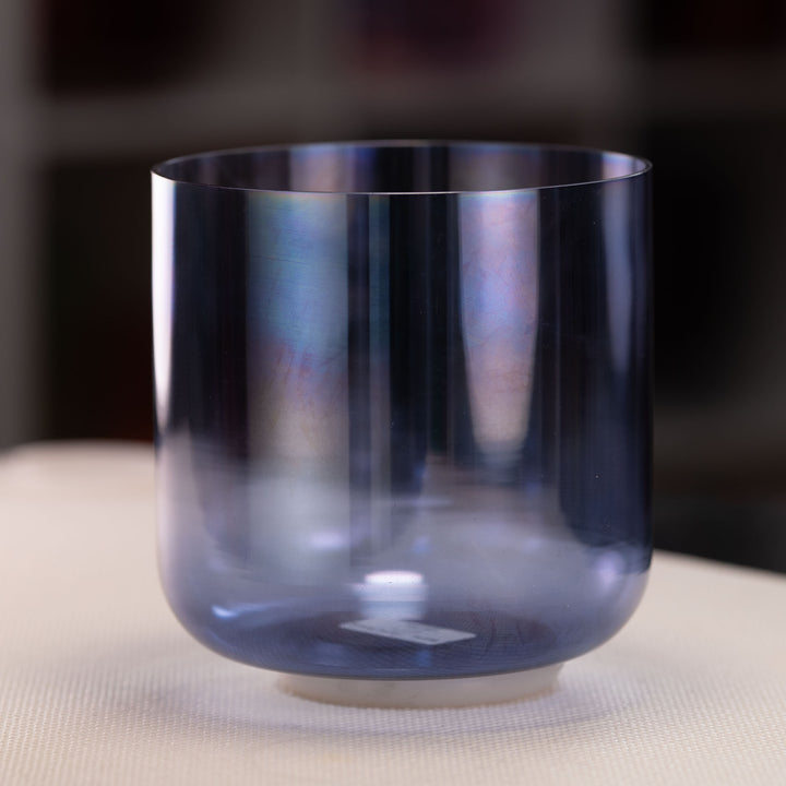 Blue crystal singing bowl on a neutral surface with a blurred background