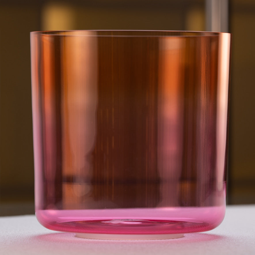 A pink and orange quartz crystal singing bowl with a smooth, reflective surface.