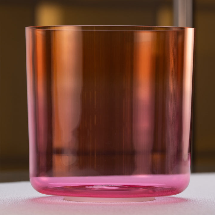 A pink and orange quartz crystal singing bowl with a smooth, reflective surface.