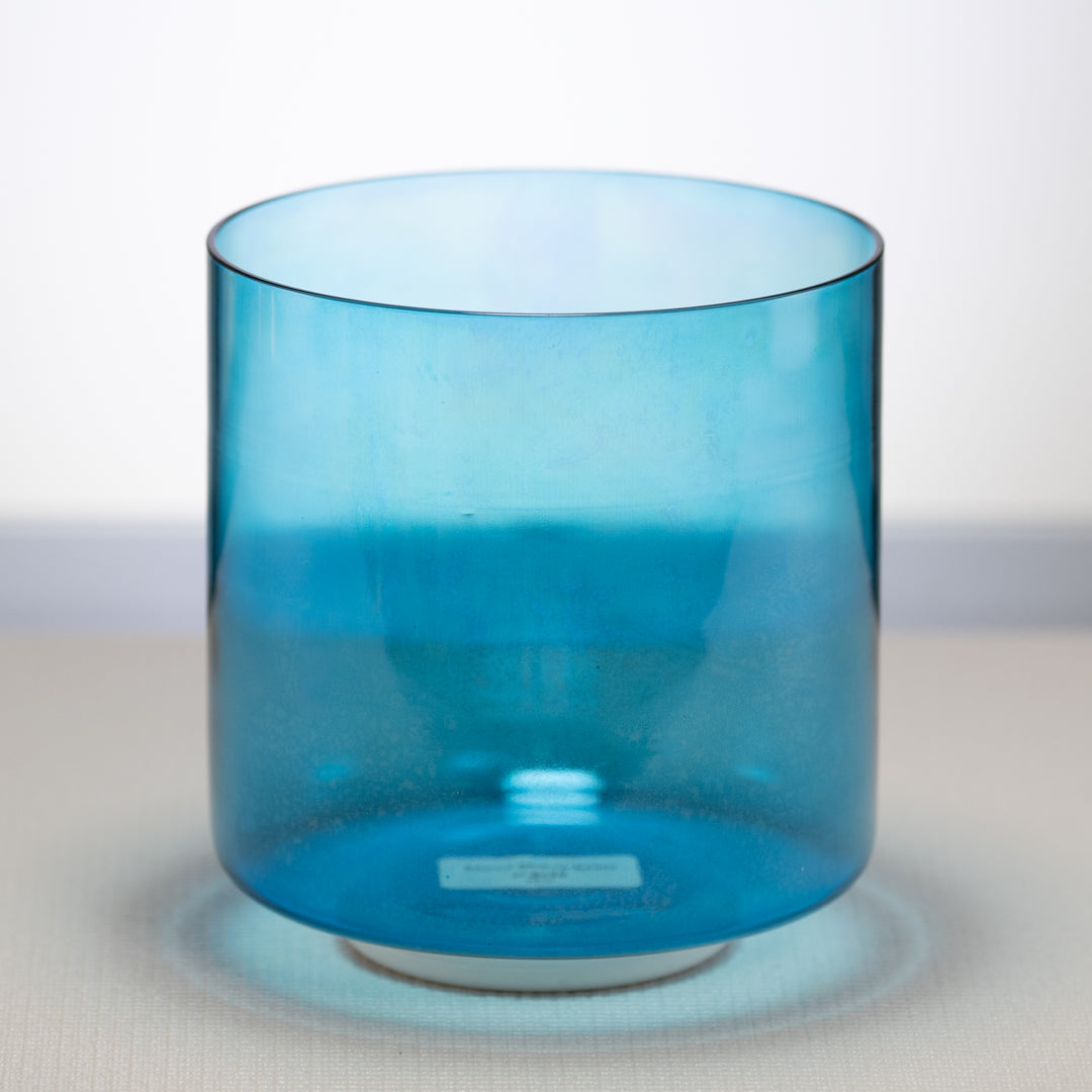 A 7-inch Caribbean Blue Crystal Singing Bowl placed on a white surface, with a translucent blue color visible.