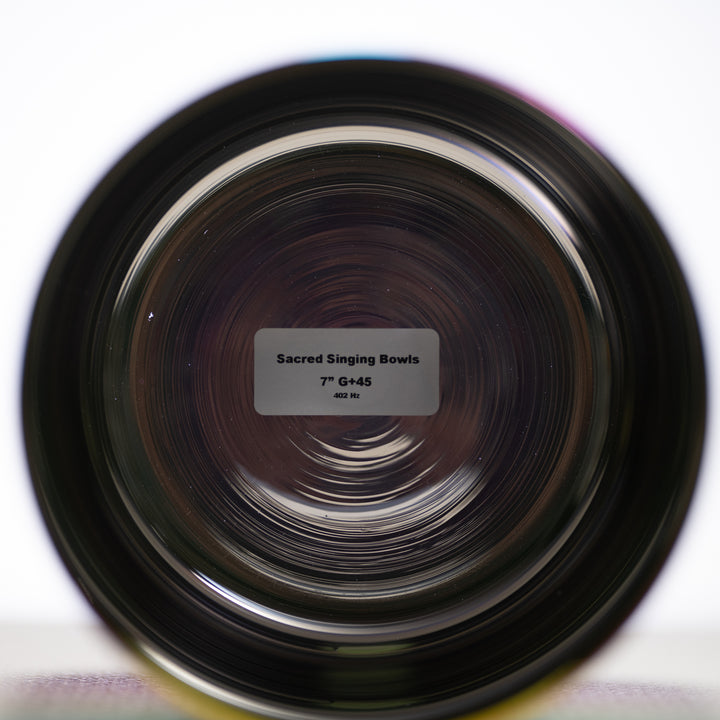 A 7 inch G+45 Celestial Rainbow Singing Bowl with a label showing the product name and size, placed on a white surface.
