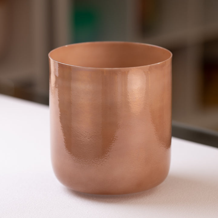 An 8.25 inch A-16 Desert Hymn Crystal Singing Bowl on a white surface, with a pearlescent light brown color.