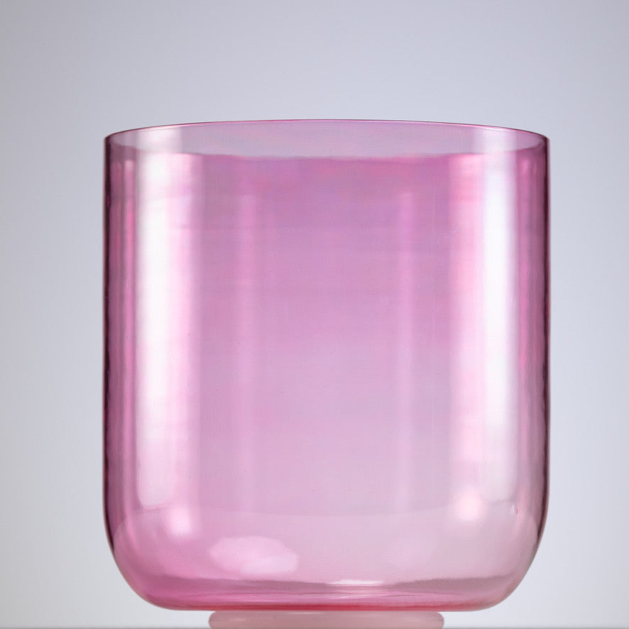 A pink crystal singing bowl, with a smooth and glossy finish, placed on a white surface.