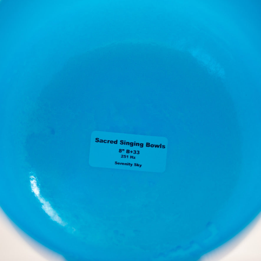 Blue singing bowl with a label indicating 'Sacred Singing Bowls' on a white background
