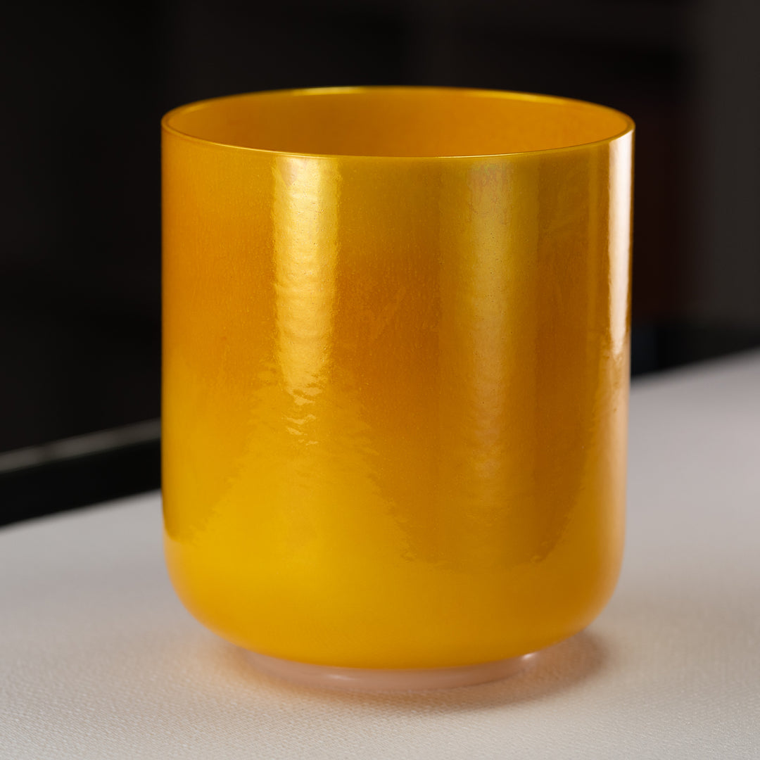A yellow, 8-inch honeycomb crystal singing bowl placed on a flat surface.