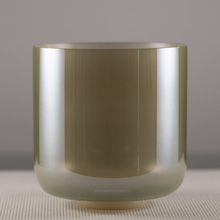 A 9.25 inch quartz crystal singing bowl with a sage green color, placed on a textured surface.