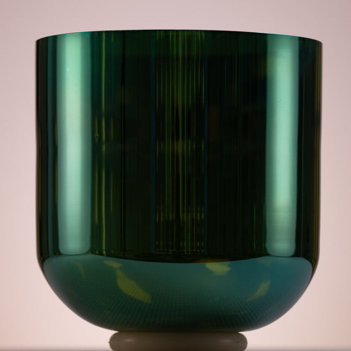 A 9.25” dark green crystal singing bowl with a gold interior, placed on a wooden surface.