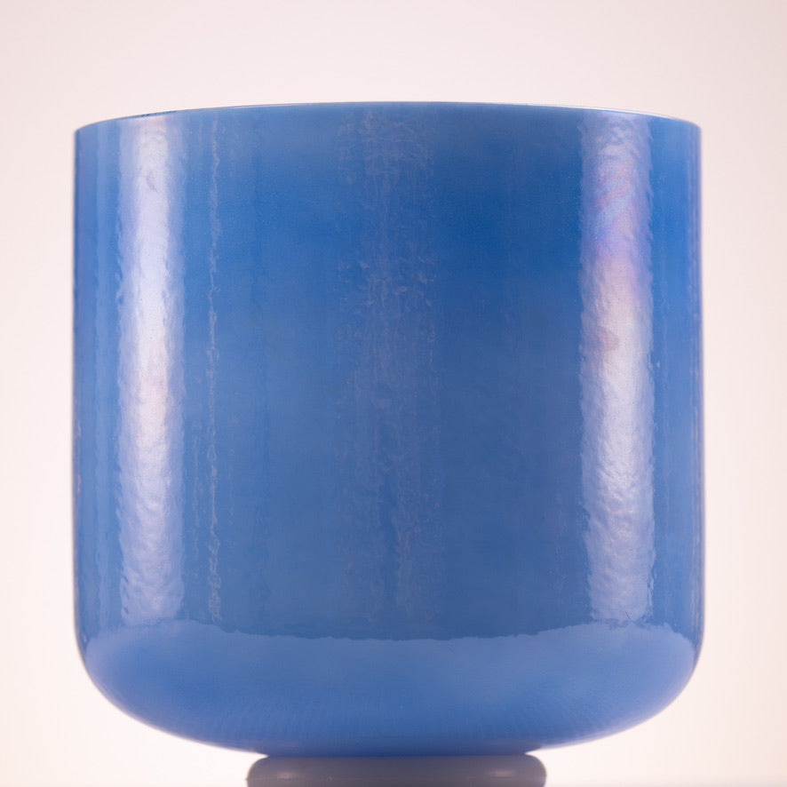 A blue crystal singing bowl with a smooth surface, displayed against a plain background.