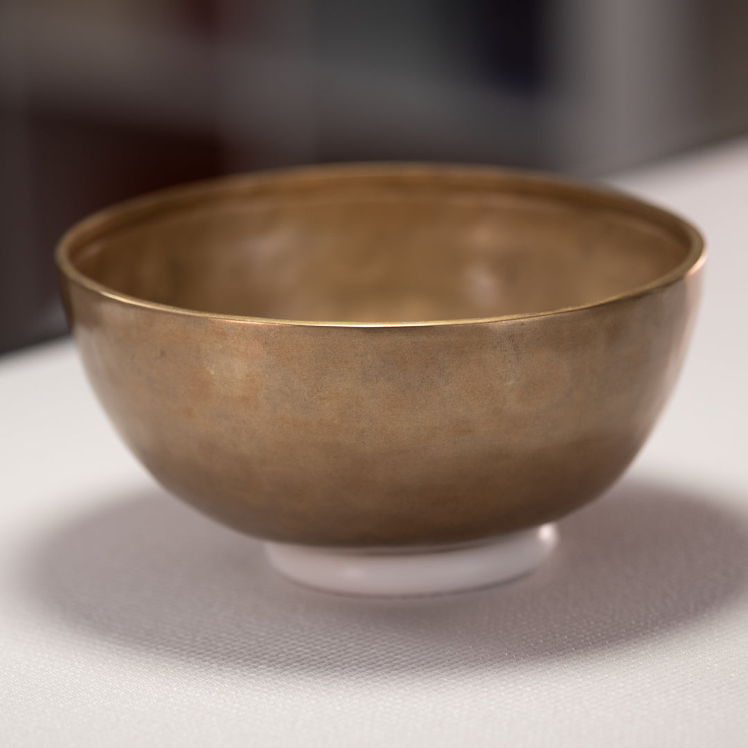 Bronze bowl on a reflective surface with a blurred background