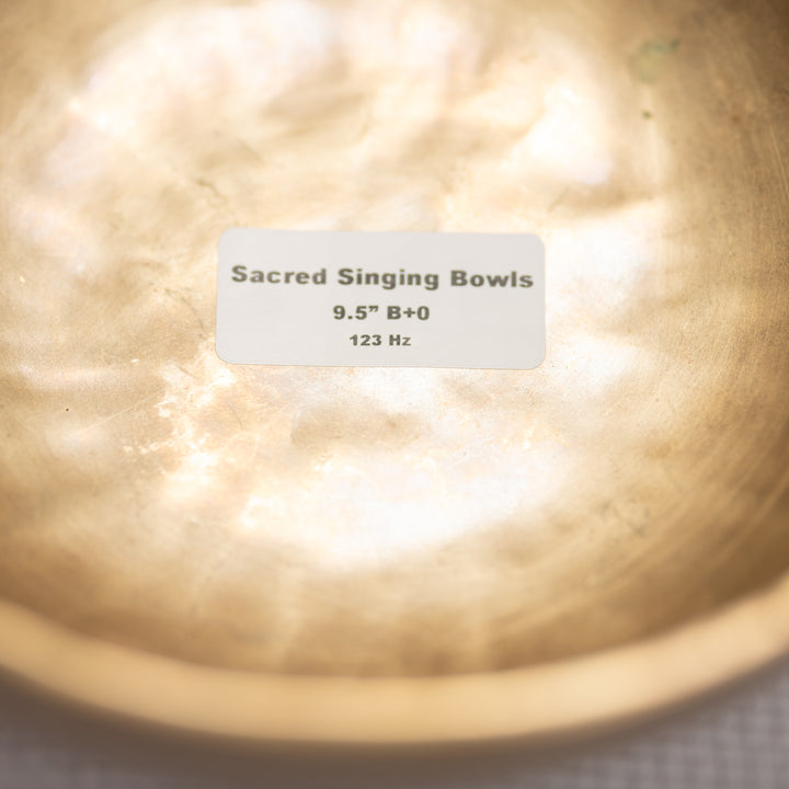 Close-up of a metal singing bowl with a label indicating specifications.