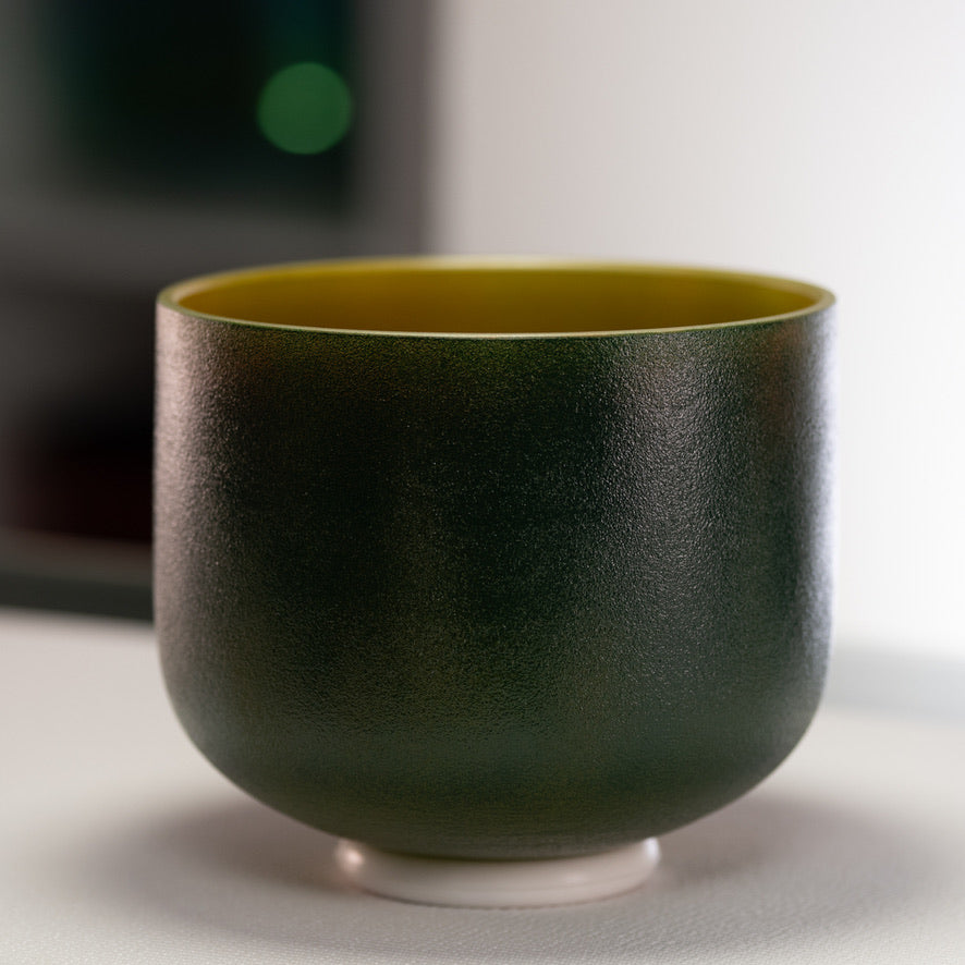 A 9-inch frosted crystal singing bowl with a green exterior and gold interior, placed on a white surface.