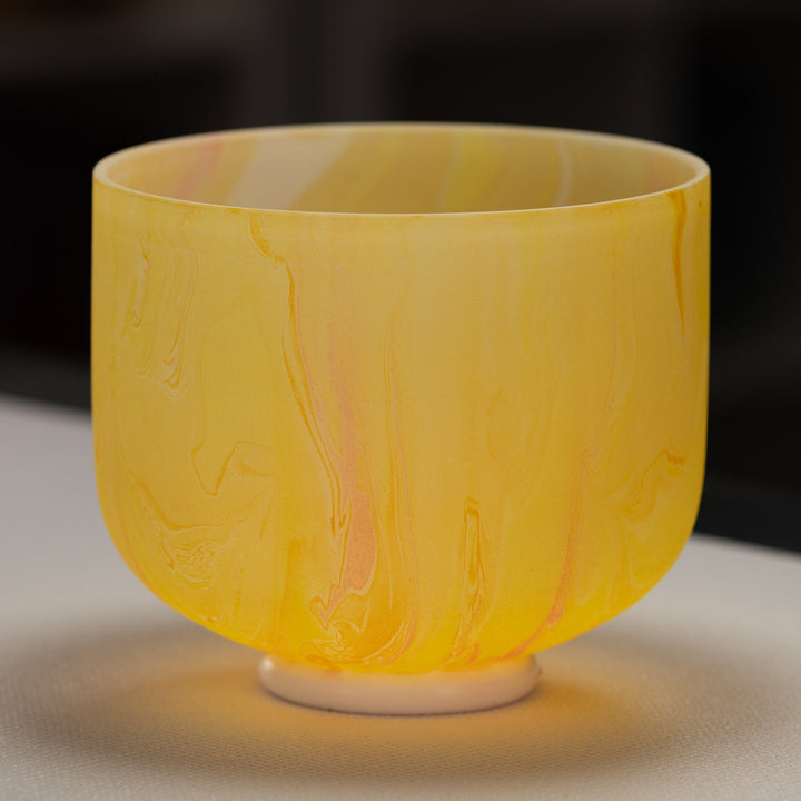 A 9-inch frosted yellow crystal singing bowl with yellow swirl patterns, placed on a flat surface.