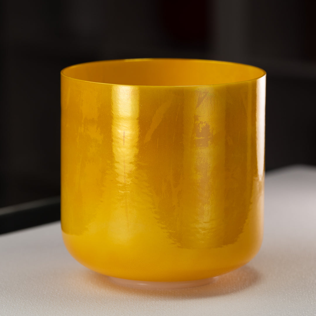 A polished golden yellow quartz crystal singing bowl with a smooth surface, displayed on a white cloth.