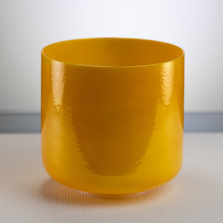 A bright yellow, 9-inch honeycomb crystal singing bowl placed on a flat surface.