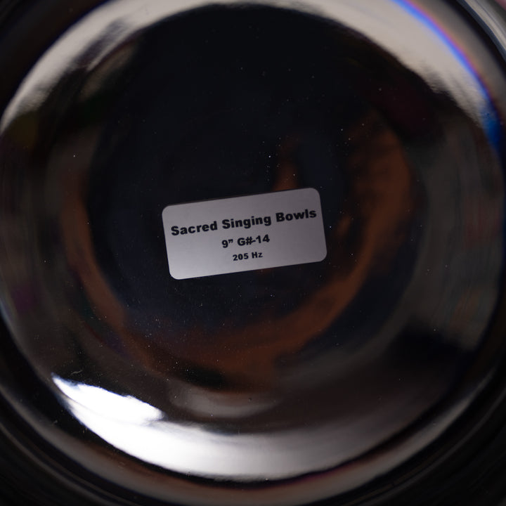 Close-up of a metallic singing bowl with a label indicating 'Sacred Singing Bowls' and specifications.