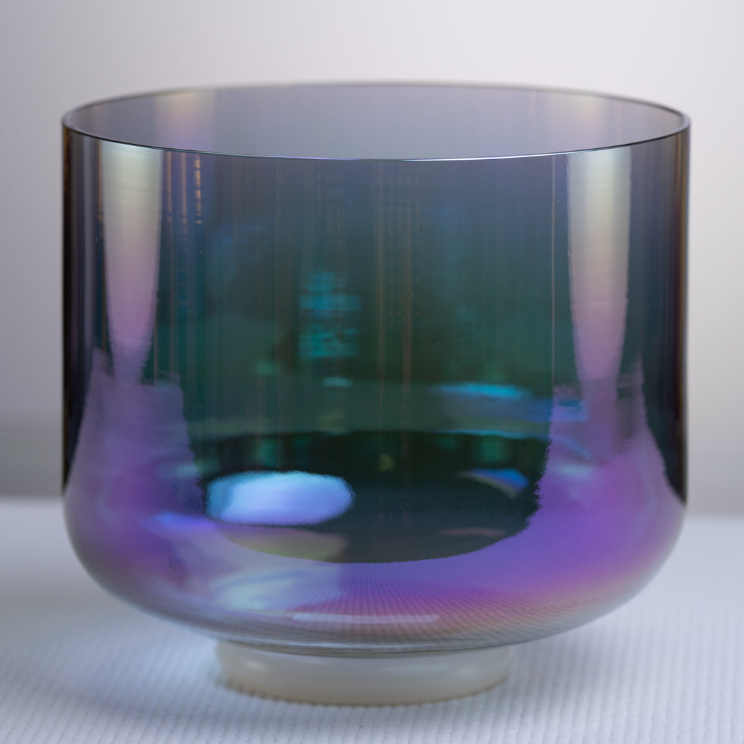 A 9 inch G#+41 Aurora Sky Crystal Singing Bowl with a reflective surface displaying a range of colors from indigo to blue.