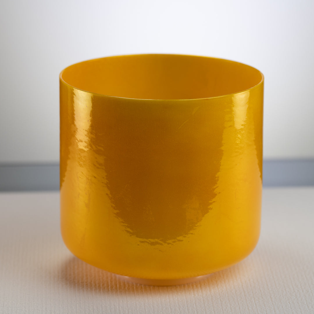 A polished yellow crystal singing bowl with a smooth, shiny surface.