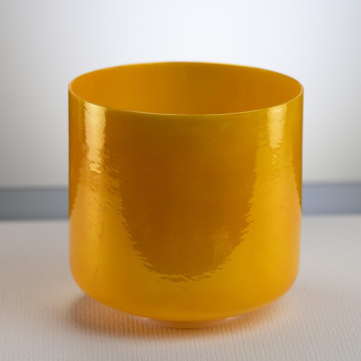A polished yellow crystal singing bowl with a smooth, shiny surface.