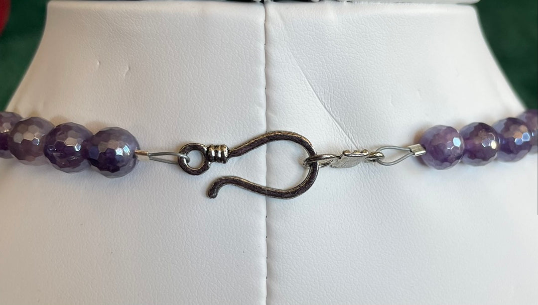 Amethyst beaded necklace with a clasp on a white tile background