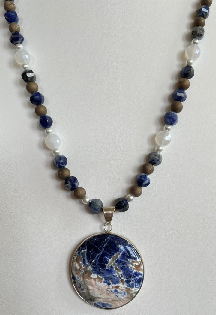 Necklace with blue and brown beads and a large round pendant on a white background