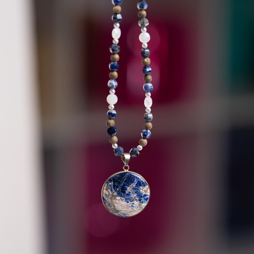 Necklace with a blue pendant against a blurred background