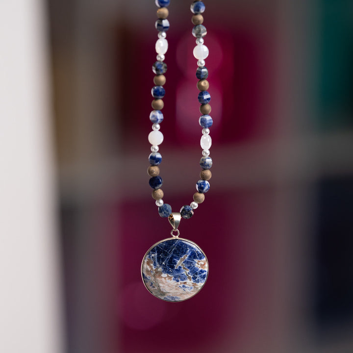 Necklace with a blue pendant against a blurred background